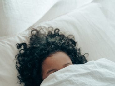 woman under white bed comforter